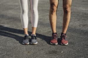 Legs and Feet of Two Anonymous Runners Standing on the Street