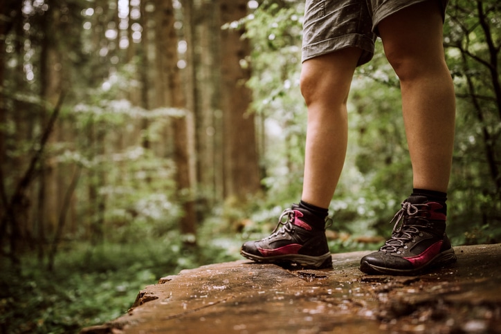 Hiker in boots standing on log in forest